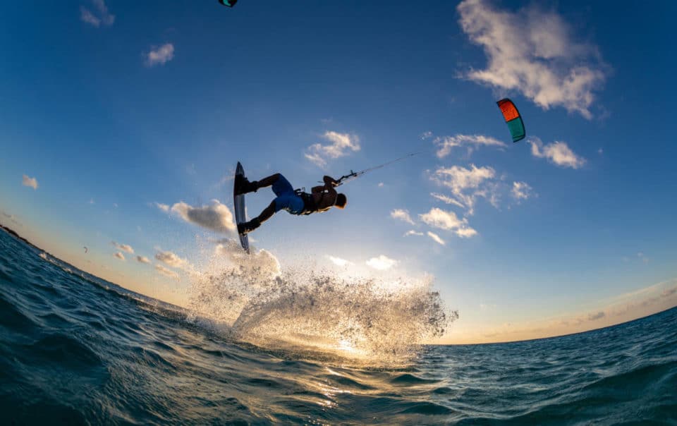 person surfing and flying a parachute at the same time in kitesurfing. Tahiti, French Polynesia