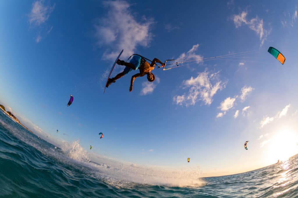 low angle shot of a person surfing and flying a parachute at the same time in kitesurfing