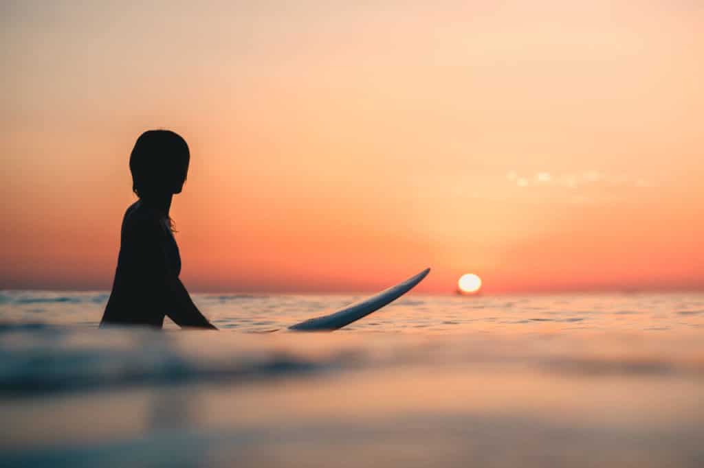 surfer on the ocean with the breathtaking sunset in the sky in the background